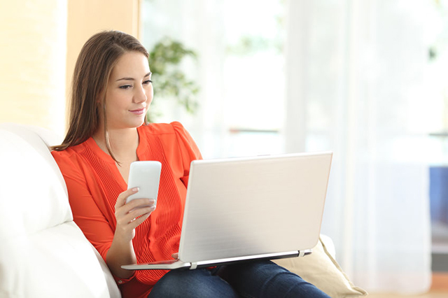 young woman smiling with laptop and smartphone